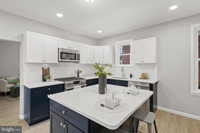 kitchen with appliances with stainless steel finishes, white cabinetry, and a kitchen island