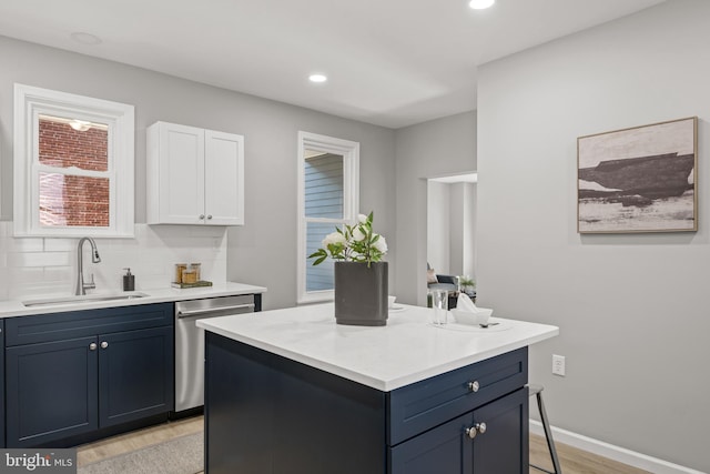 kitchen with white cabinetry, dishwasher, sink, tasteful backsplash, and a kitchen island