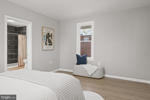 bedroom with connected bathroom and hardwood / wood-style flooring