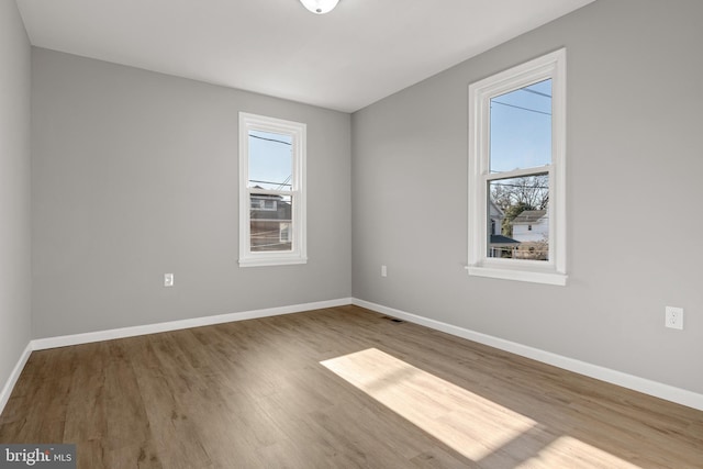 empty room with hardwood / wood-style floors and a wealth of natural light