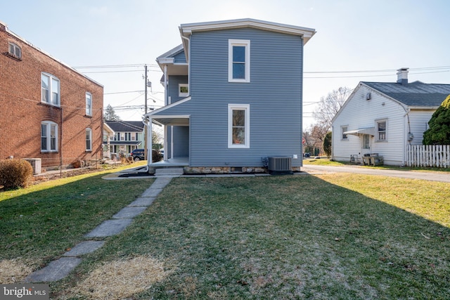 back of house with central air condition unit and a lawn