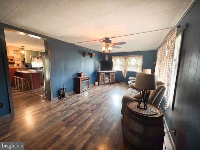 living area featuring wooden walls, ceiling fan, and dark wood-type flooring