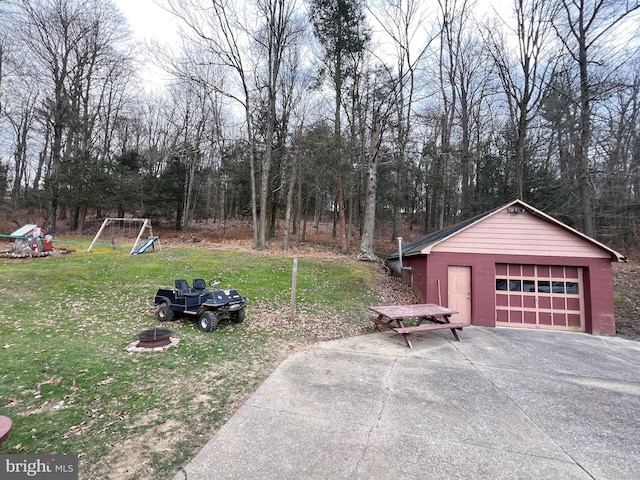 view of yard featuring a garage, a playground, and an outbuilding