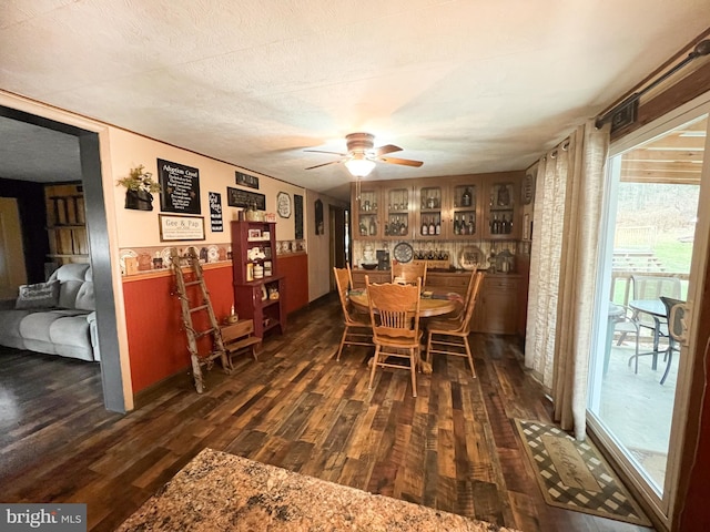 dining space with ceiling fan, dark wood-type flooring, and a textured ceiling