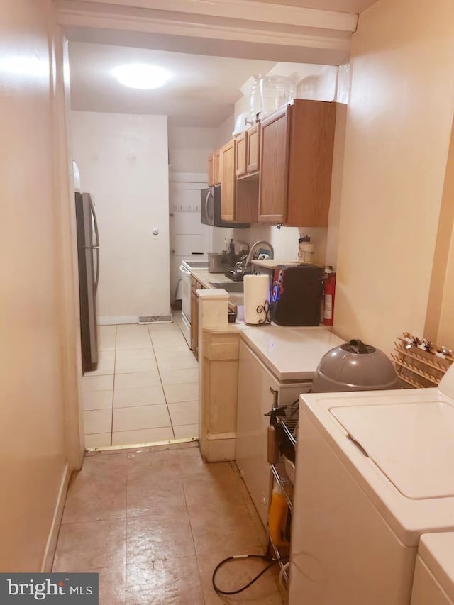 kitchen with stainless steel appliances, washer and dryer, and light tile patterned floors