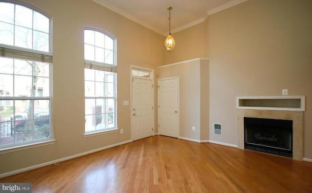 doorway with wood-type flooring, ornamental molding, and a high ceiling