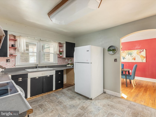 kitchen with backsplash, white fridge, light wood-type flooring, and sink