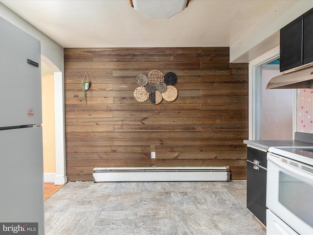 kitchen featuring wood walls, a baseboard radiator, and white appliances