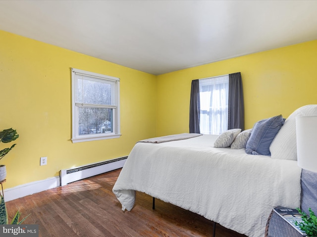 bedroom with dark hardwood / wood-style floors and a baseboard heating unit