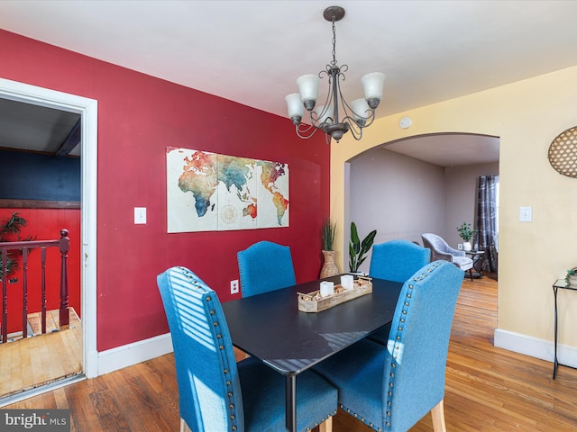 dining space featuring wood-type flooring and an inviting chandelier