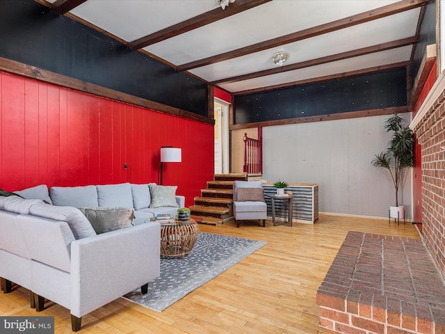 living room with beam ceiling, wood walls, and hardwood / wood-style floors