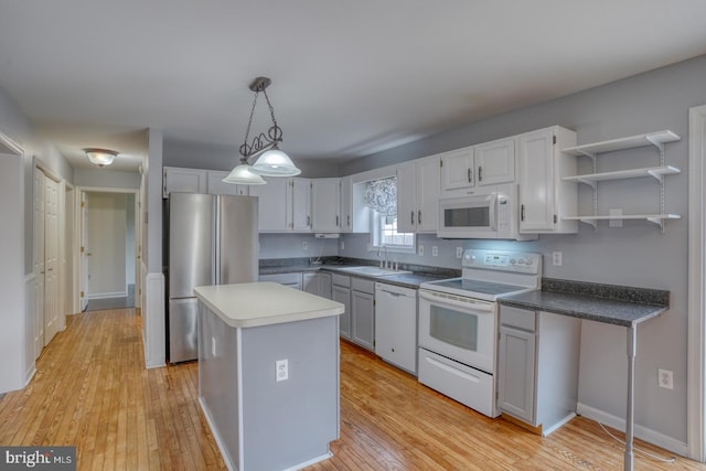 kitchen featuring white cabinetry, decorative light fixtures, white appliances, a kitchen island, and light wood-type flooring