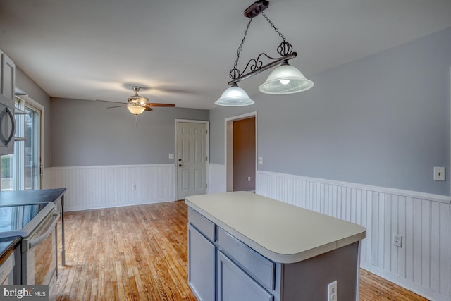 kitchen featuring a center island, decorative light fixtures, ceiling fan, and light hardwood / wood-style floors