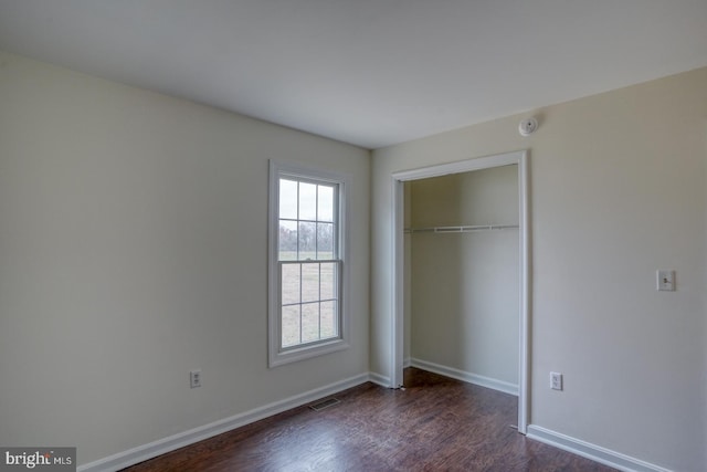 unfurnished bedroom with a closet and dark hardwood / wood-style floors