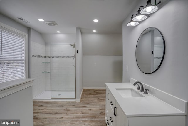 bathroom with tiled shower, vanity, and hardwood / wood-style flooring