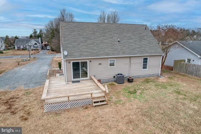 back of property with a deck, central air condition unit, and a yard