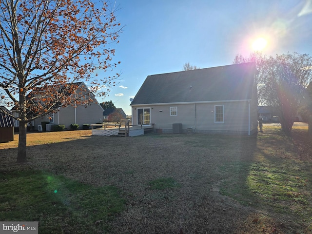 rear view of property with a yard, cooling unit, and a deck