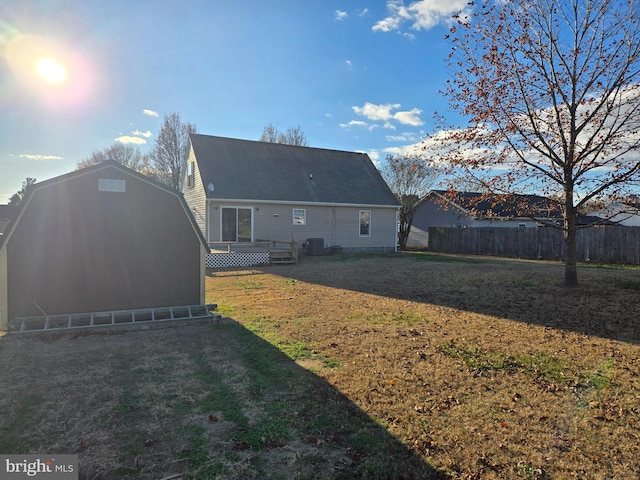 rear view of house with a lawn, central air condition unit, and a storage unit