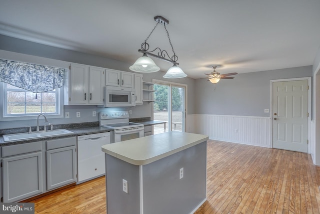 kitchen featuring white appliances, sink, ceiling fan, decorative light fixtures, and a kitchen island