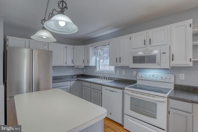 kitchen featuring white appliances, sink, light wood-type flooring, decorative light fixtures, and white cabinetry