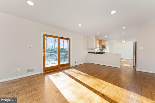 unfurnished living room with light hardwood / wood-style floors and sink