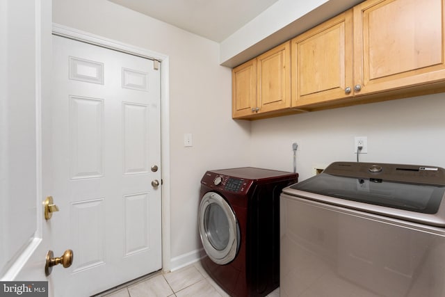 laundry area with cabinets, independent washer and dryer, and light tile patterned floors