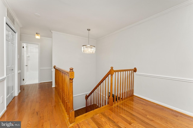 staircase with crown molding, a chandelier, and hardwood / wood-style flooring