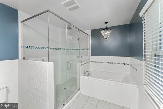 bathroom featuring tile patterned flooring, a notable chandelier, and shower with separate bathtub