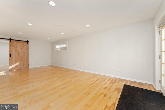 empty room with light wood-type flooring and a barn door