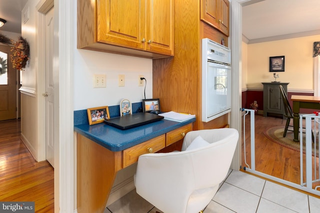 kitchen featuring light hardwood / wood-style floors, ornamental molding, and white oven