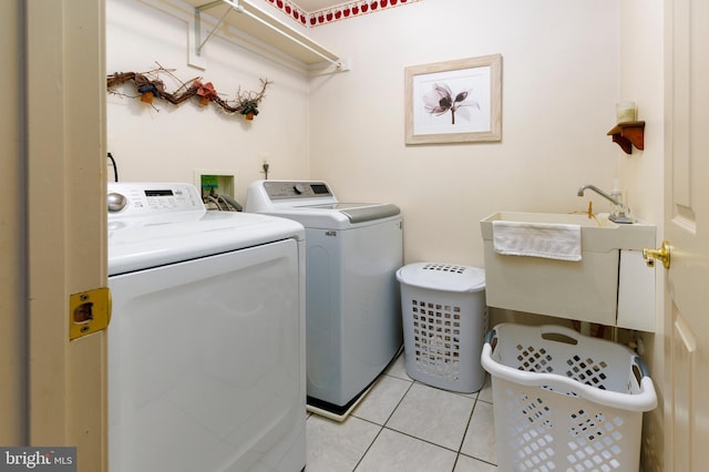 washroom with light tile patterned flooring, washing machine and dryer, and sink