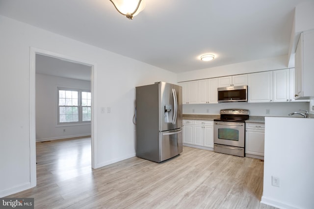 kitchen featuring sink, white cabinetry, stainless steel appliances, and light hardwood / wood-style flooring