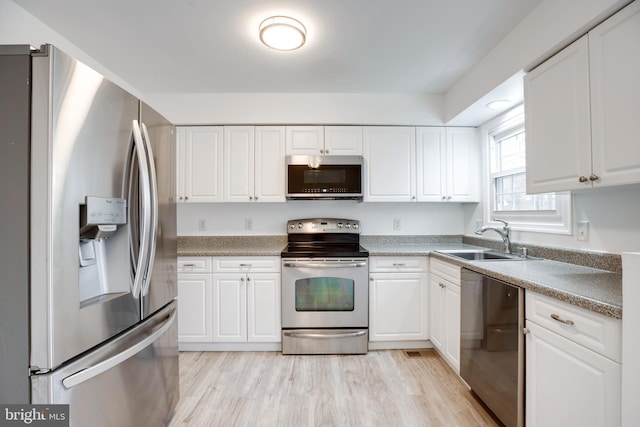 kitchen with white cabinets, appliances with stainless steel finishes, light hardwood / wood-style floors, and sink