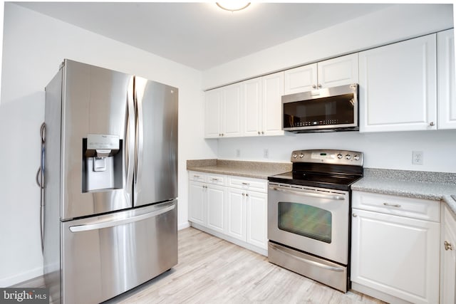 kitchen with white cabinetry, stainless steel appliances, and light hardwood / wood-style floors