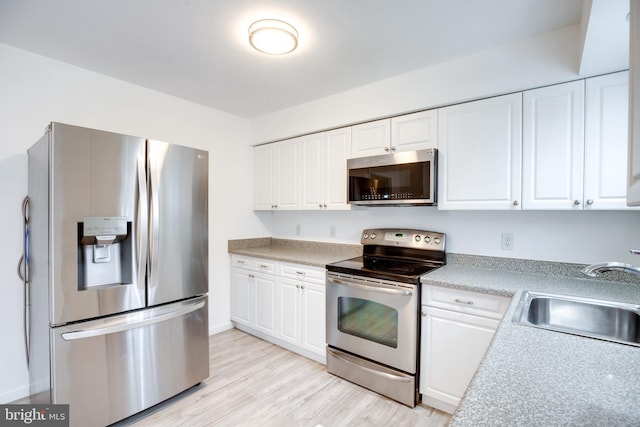 kitchen featuring white cabinets, light wood-type flooring, sink, and appliances with stainless steel finishes