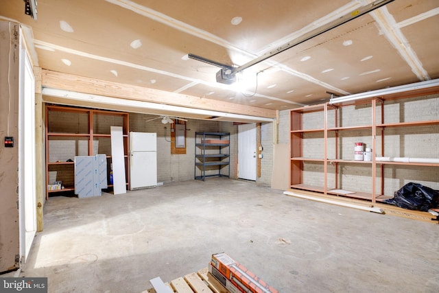 garage featuring white fridge, a garage door opener, and electric panel