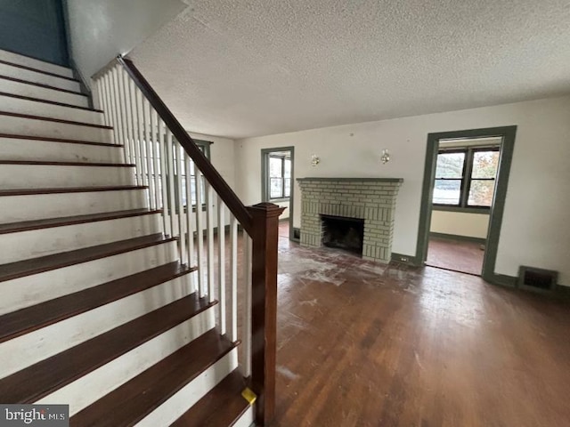 interior space with wood-type flooring, a textured ceiling, a brick fireplace, and a wealth of natural light