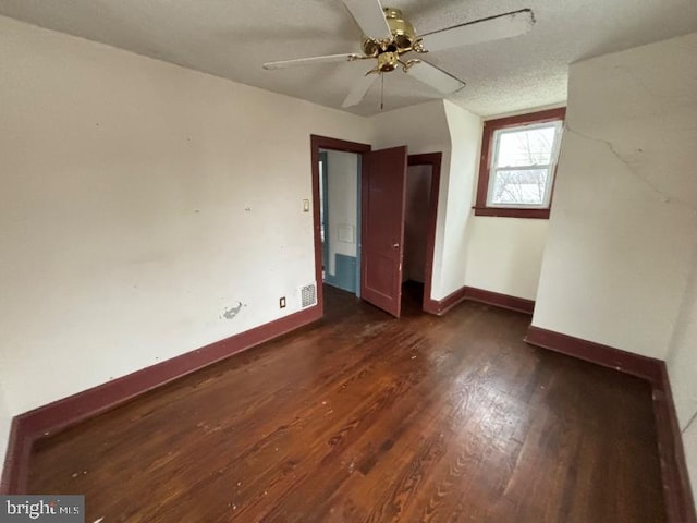 unfurnished bedroom featuring ceiling fan, dark wood-type flooring, and a textured ceiling