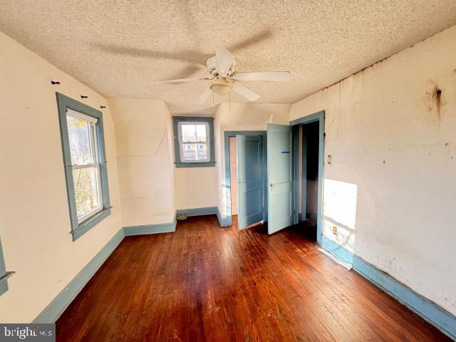 unfurnished bedroom featuring vaulted ceiling, ceiling fan, dark hardwood / wood-style floors, and a textured ceiling