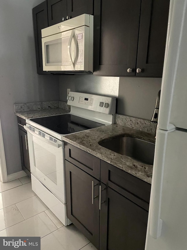 kitchen with light stone countertops, sink, light tile patterned floors, and white appliances