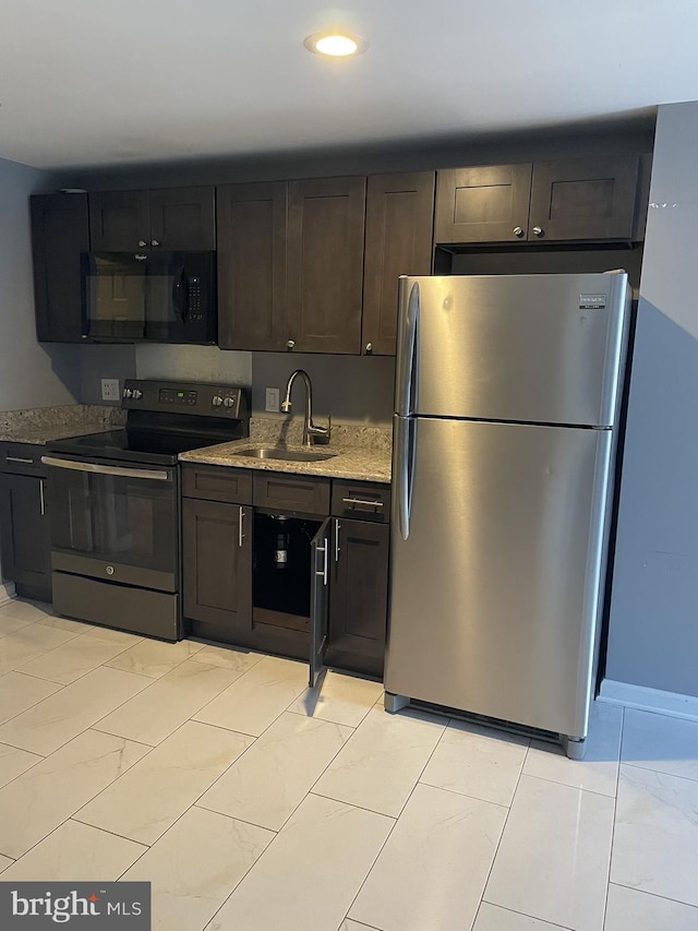 kitchen with light stone counters, sink, stainless steel appliances, and dark brown cabinets