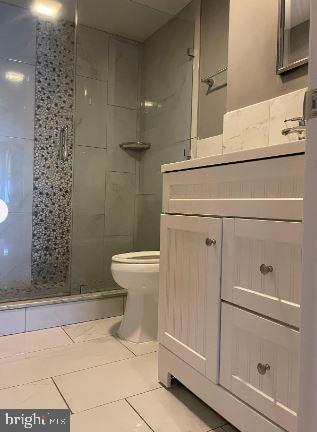 bathroom featuring tile patterned floors, vanity, toilet, and a shower with shower door