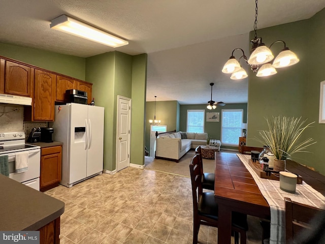 kitchen featuring pendant lighting, white appliances, lofted ceiling, ceiling fan with notable chandelier, and tasteful backsplash