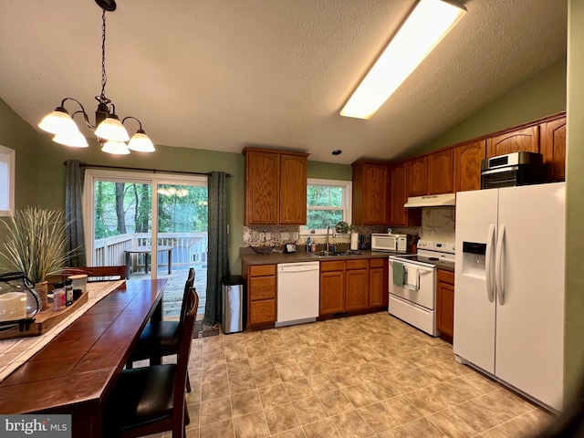 kitchen with white appliances, backsplash, sink, hanging light fixtures, and a chandelier