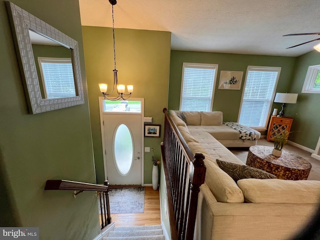 entryway featuring ceiling fan with notable chandelier, a textured ceiling, hardwood / wood-style flooring, and a wealth of natural light