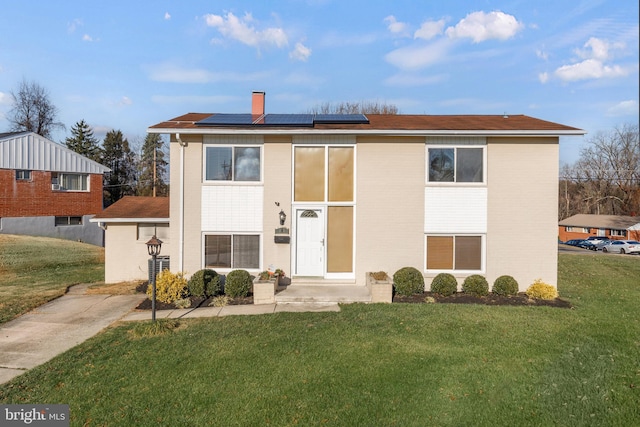 view of front of home with a front yard and solar panels