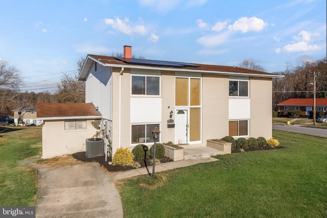 view of front facade featuring solar panels, cooling unit, and a front lawn