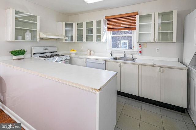 kitchen featuring light tile patterned floors, sink, white appliances, white cabinets, and kitchen peninsula