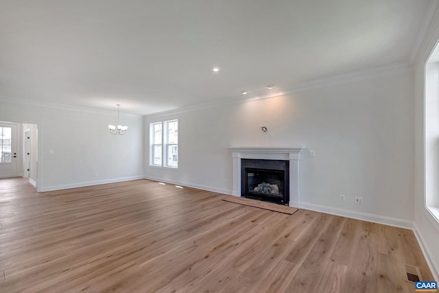 unfurnished living room featuring light hardwood / wood-style floors, crown molding, and an inviting chandelier