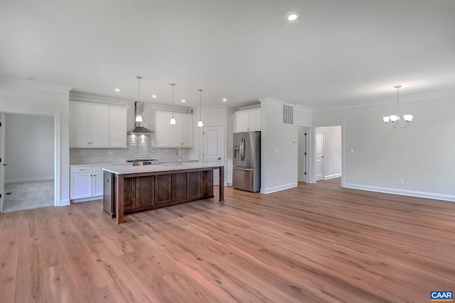 kitchen featuring decorative light fixtures, light hardwood / wood-style floors, wall chimney range hood, and stainless steel refrigerator with ice dispenser